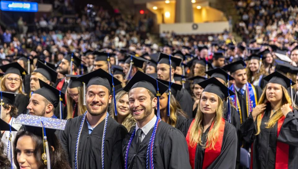 A crowd of UNE graduates smiles for a photo