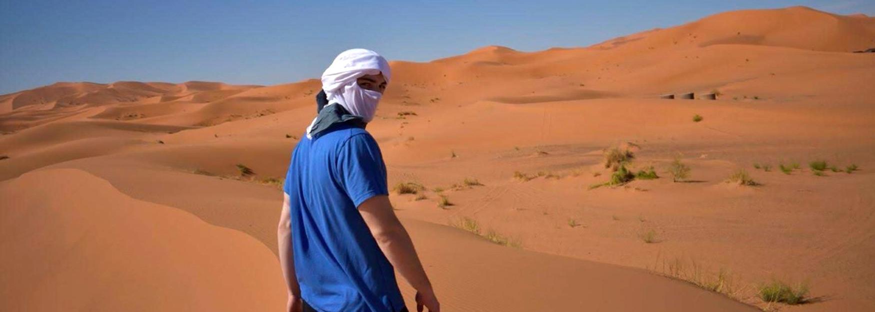 Devin Jozokos站在撒哈拉沙漠中，回头看着镜头