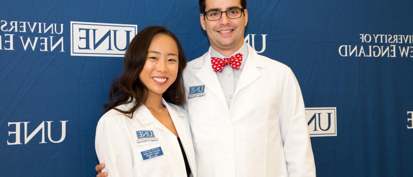 U N E College of Pharmacy students in front of UNE banner after White Coat Ceremony
