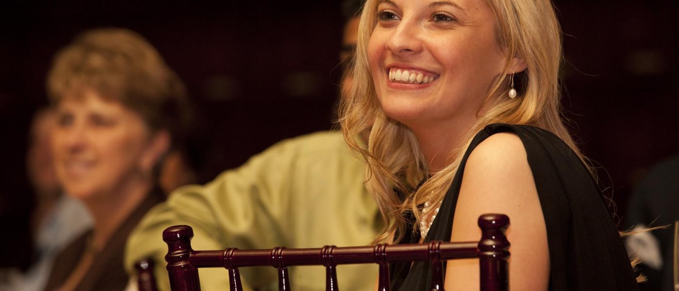一名英国东北大学药学专业的女学生微笑着坐在一个正装场合  