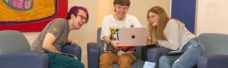Three University of New Engl和 students sit together around a laptop