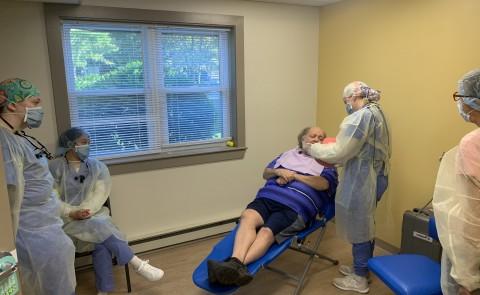 一位坐在牙医椅上的病人正在接受学生的咨询