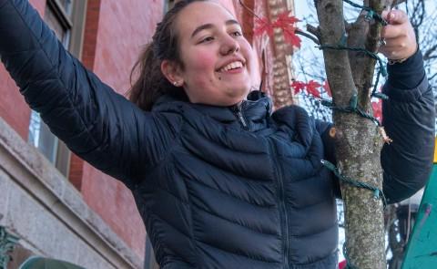 A student smiles as she hangs lights in front of Biddeford's City Theater