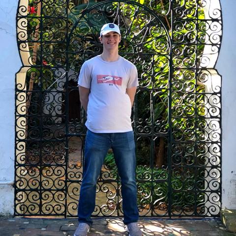 Devin Jozokos stands in front of a decorated metal doorway in Morocco, smiling at the camera