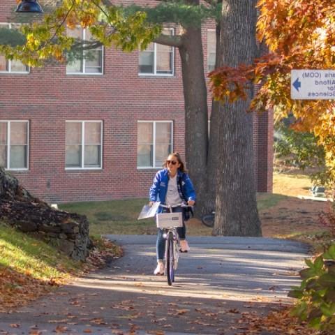 A UNE student bikes through campus in the fall 